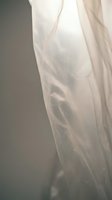 Soft translucent white fabric flowing gracefully with gentle folds and creases creating elegant drapery against neutral background for fashion design.