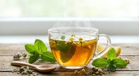 Herbal tea in glass cup with fresh mint leaves on wooden table. Hot beverage for relaxation and wellness lifestyle.