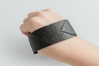 Wrist wrapped in dark gray elastic bandage for injury support and pain relief during sports or rehabilitation therapy.