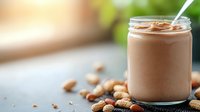 Creamy chocolate almond smoothie in glass jar with scattered nuts on rustic wooden surface, natural bokeh background, healthy protein drink concept.