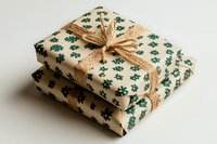 Eco-friendly gift wrapping with green snowflake pattern on cream paper, natural jute twine bow, stacked presents on white background for sustainable holidays.