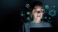 Young Caucasian woman working on laptop with futuristic digital network icons and data visualization overlay in dark environment for technology concepts.