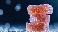 Orange gummy candy stack with sugar coating on dark blue background with bokeh lights for confectionery and sweet treat marketing.