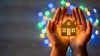 Hands protecting glowing house symbol with colorful bokeh lights background. Home insurance, real estate protection and property security concept.