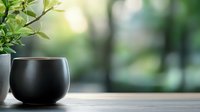 Modern black ceramic cup on wooden table with green plant in blurred natural background for coffee tea lifestyle home decor kitchen dining relaxation.