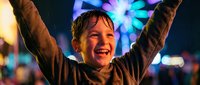 Happy young boy with arms raised celebrating at night carnival with colorful ferris wheel lights creating joyful childhood moment of pure excitement and fun.