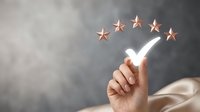 Business professional hand pointing at five golden stars rating system for customer satisfaction and quality service evaluation.