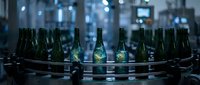 Rows of elegant champagne bottles with gold labels arranged on a reflective surface against a blurred urban skyline at night, suitable for luxury beverage marketing and celebration concepts.