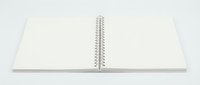 Open blank spiral notebook with white pages lying flat on white background, ready for writing, sketching, or design projects.