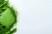 Fresh green matcha tea powder scattered with natural tea leaves creates organic border composition on white background, copy space for wellness design.