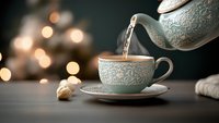 Steaming hot tea poured from ornate mint green teapot into matching porcelain cup with delicate floral pattern against blurred bokeh lights background.