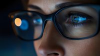 Close-up portrait of young woman wearing eyeglasses with digital screen reflection in lens, technology and modern lifestyle concept for business presentations.