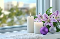 White candles and purple lily flowers on windowsill with silver and purple Christmas ornaments create serene holiday atmosphere near window with soft natural light.