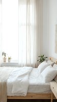 Minimalist bedroom interior with white linen bedding, wooden bed frame, sheer curtains and green plants on windowsill creating serene scandinavian atmosphere.