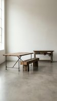 Rustic wooden dining table with bench and sideboard in minimalist interior with concrete floor and natural window light for modern farmhouse decor.