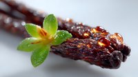 Aromatic vanilla pods with fresh green orchid flower and water drops on dark wooden surface, macro food photography for culinary and fragrance designs.
