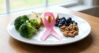 Healthy nutrition concept with pink ribbon symbol, fresh broccoli, apple slices, blueberries and walnuts on white plate for cancer awareness and prevention.
