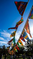 Colorful prayer flags with ethnic patterns flutter in wind against blue sky at outdoor festival celebration for cultural events and spiritual ceremonies.