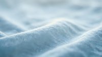 Close-up of white fabric texture with soft folds and gentle waves, suitable for textile, fashion, and design projects.