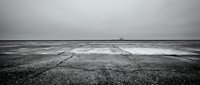 Dramatic black and white seascape with waves crashing onto pebble beach under moody overcast sky, minimalist coastal landscape for artistic projects.