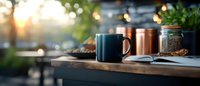 Cozy morning coffee setup with dark mug and copper cup on wooden table with warm bokeh lights creating peaceful breakfast atmosphere for cafes and lifestyle.