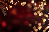 Warm holiday background with glowing string lights and pine branch creating festive bokeh atmosphere for seasonal celebrations and winter decorations.
