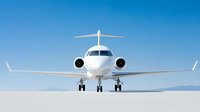 Modern white private jet aircraft on runway against blue sky background. Front view of business aviation plane with landing gear down on bright sunny day.