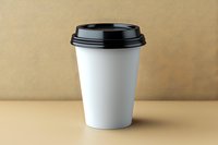 White paper coffee cup with black lid on beige background. Mockup for branding and logo design isolated with copy space for cafe and restaurant promotion.