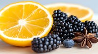Fresh orange slice with ripe blackberries, blueberry and star anise on white surface, macro food photography with soft natural lighting.