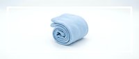 Soft light blue terry towel rolled up, isolated on white background. Fluffy cotton bath accessory for spa, hotel, and bathroom design projects.