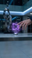 Businessman hand interacting with futuristic holographic interface displaying purple atomic model in modern laboratory setting for innovation concepts.
