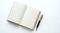 Open blank notebook with two pens on white background, suitable for business planning, journaling, education, and creative writing projects.