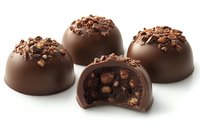 Dark chocolate truffles with crushed nuts topping, one cut in half showing rich ganache filling with crunchy pieces inside, arranged on white background.