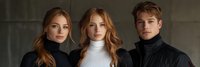 Young diverse models wearing turtleneck sweaters pose together against dark background, showcasing modern minimalist fashion style and natural makeup for autumn collection.