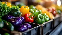 Fresh organic vegetables in grocery store display, including vibrant purple eggplants, colorful bell peppers, and leafy greens arranged in retail boxes with soft lighting.