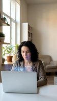 Professional Hispanic woman working on laptop with AI assistant interface in modern home office with natural lighting and plants.