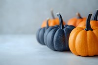 Orange and dark blue decorative pumpkins arranged on light gray background, creating seasonal contrast for autumn decor and Halloween designs.