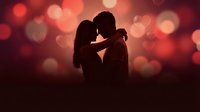 Romantic couple silhouette embracing against warm bokeh lights background for Valentine's Day, anniversary, love, wedding, and relationship concepts.
