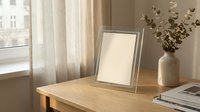 Minimalist silver photo frame with blank canvas on wooden table, soft natural light, eucalyptus vase, cozy Scandinavian interior decor.
