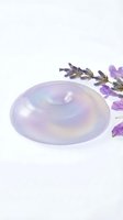 Translucent lavender soap bar with central indentation displayed alongside dried lavender flowers on white background, suitable for spa, wellness and beauty product marketing.