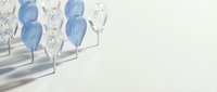 Blue and clear glass balloons floating with ribbons casting soft shadows on white background for party celebration design.