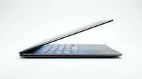 Thin laptop computer with open screen displaying keyboard and touchpad, isolated on white background for web design and technology marketing use.
