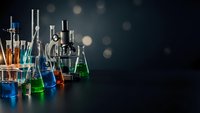 Laboratory glassware with colorful chemical solutions on dark background with bokeh lights for scientific research and experimentation concepts.