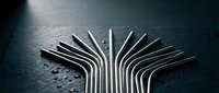 Metallic drinking straws arranged in artistic fan pattern on dark surface with water droplets creating modern sustainable lifestyle concept.