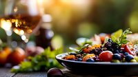 Fresh mixed berries and grapes on plate with wine glass in warm sunlight creating elegant dining atmosphere for healthy eating and gourmet lifestyle.