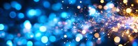 Magical blue and gold bokeh lights with glowing sparkles and particles creating dreamy festive atmosphere. Abstract blurred background for celebrations and holidays.