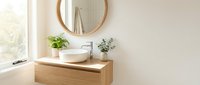Modern minimalist bathroom interior with wooden vanity, round mirror, white vessel sink and green plants creating spa-like atmosphere for home design.