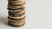 Stack of natural wood slices with bark edges on neutral background for rustic crafting and DIY projects.
