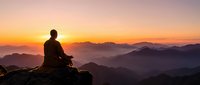 Silhouette of person meditating on mountain peak at sunrise with layered mountain ranges and golden sky. Peaceful mindfulness and spiritual wellness concept.