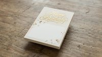 Elegant cream birthday greeting card with gold foil lettering on rustic wooden surface for celebration and party invitations.